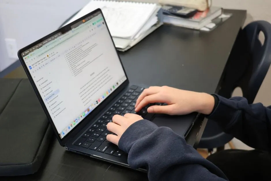 A Year 4 student typing a spelling answer on a laptop at the kitchen bench