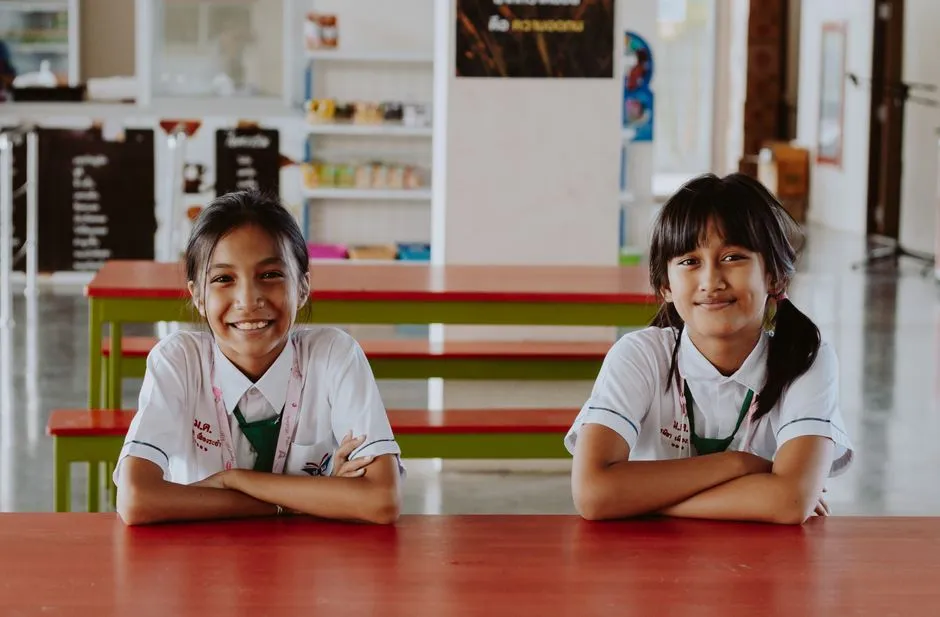 Two primary school kids sharing one tablet at a kitchen table, taking turns tapping quiz answers
