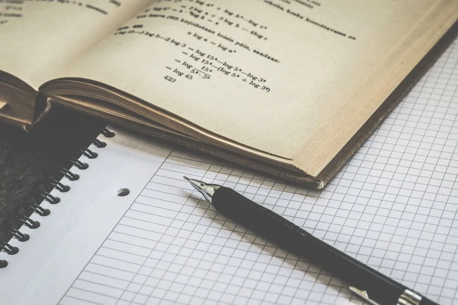 An exercise book open beside a phone showing a fractions round with a pizza split into quarters